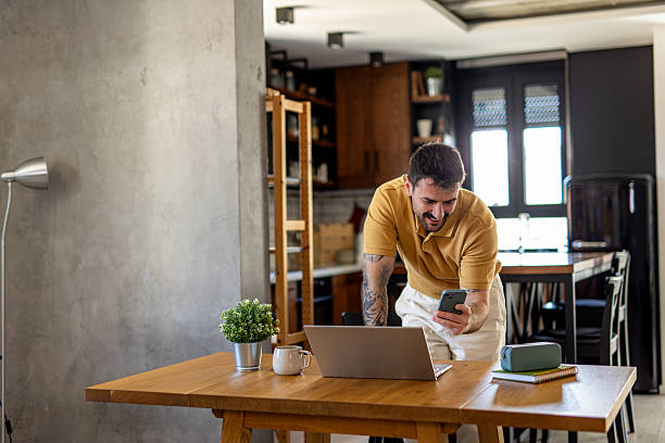 istock Freelancer smiling and using smartphone in his modern apartment 2211001134