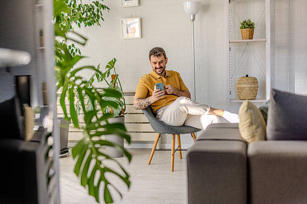 Young man relaxing on chair using mobile phone at home