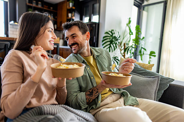 istock Couple enjoying takeout pasta on the sofa at home 2211004152