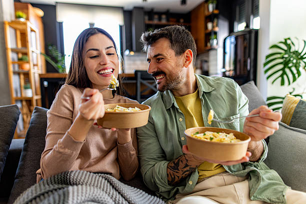 istock Happy couple eating pasta from takeaway boxes at home 2211004159