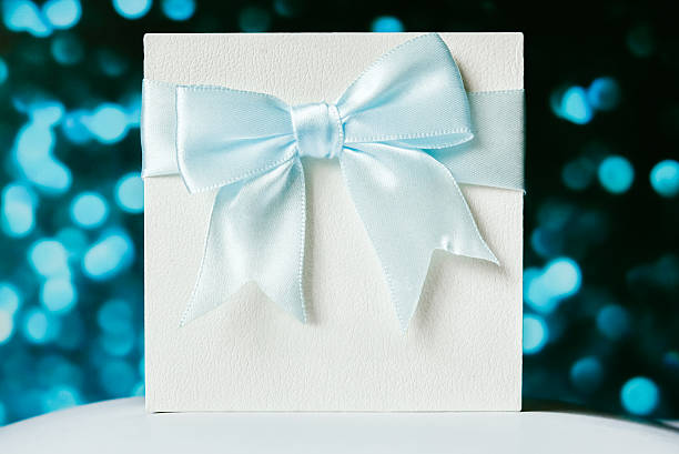 istock White luxury gift box with ribbon bow on soft blue bokeh background perfect for elegant gift presentations 2211004262