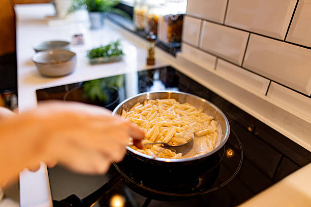 istock Chef cooking pasta with creamy sauce in a pan 2211005955