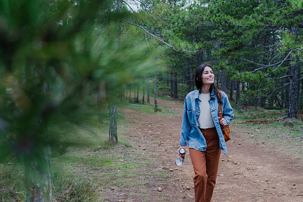 Young woman exploring a forest path, enjoying the tranquility of nature