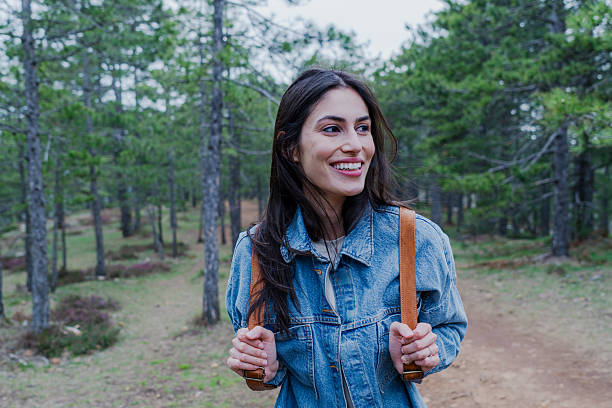 istock Young woman exploring a forest trail, enjoying the nature and smiling 2211006843
