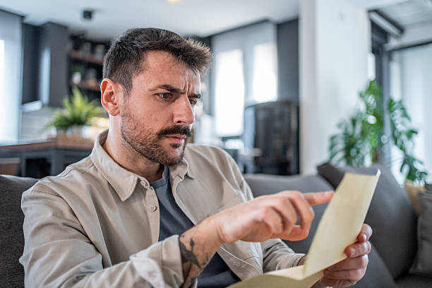 istock Worried man reading important documents at home 2211007003