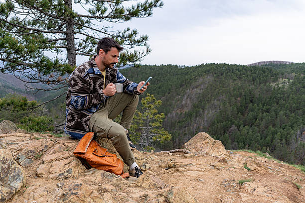istock Hiker enjoying coffee and using smartphone on mountain top 2211007152