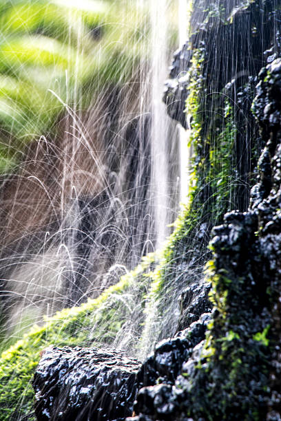 Water drops jumping from rock. Small waterfall, close up view. Water cascade.