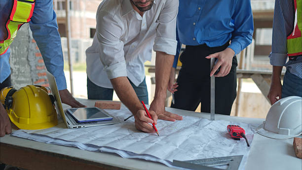 istock Group of architects and engineers work together to assess the residential home construction site's progress 2211008111