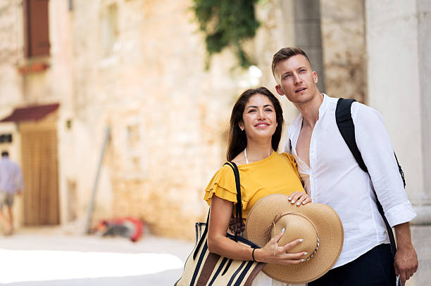 Beautiful young couple tourists, walking and talking throughout old city Pula Croatia