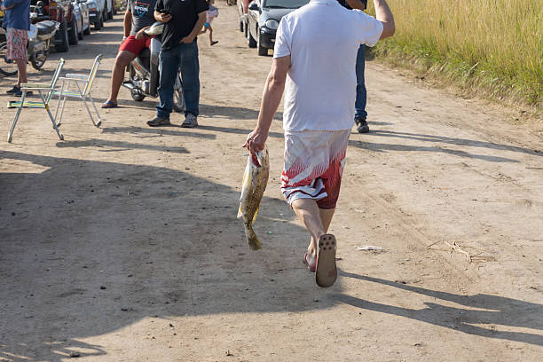 January 12, 2020. Necochea, Buenos Aires, Argentina. A fisherman holding a fish by the gills with his fingers for a fishing contest on the banks of the Quequén River.