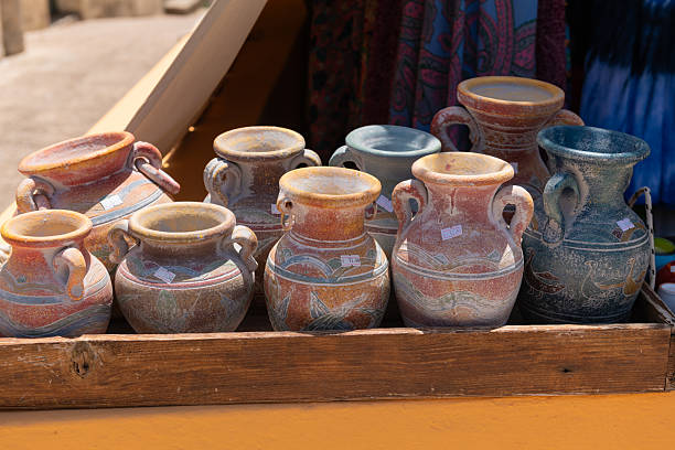 A collection of brown ceramic mugs and pitchers. The mugs and pitchers are of various sizes and shapes, and they are arranged in a way that makes them look like a display. Scene is warm and inviting