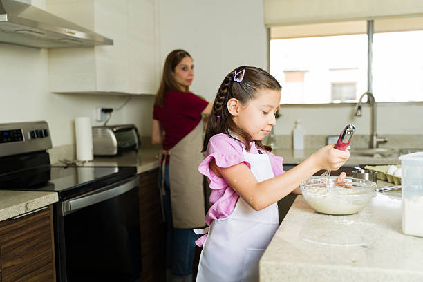 istock Daughter whisking ingredients while baking with mother in kitchen 2211023961