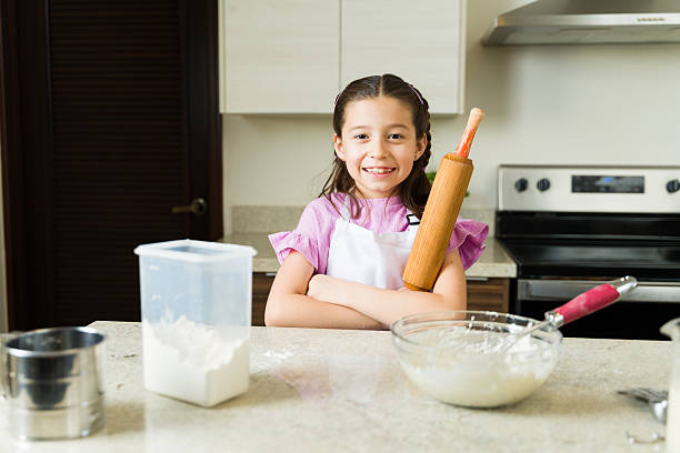 istock Cute little girl holding rolling pin preparing dough in kitchen 2211023967