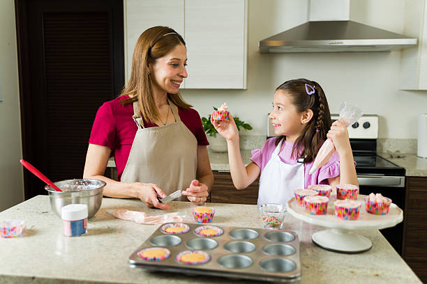 istock Happy family baking and decorating cupcakes together in kitchen 2211024227