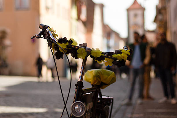 Vintage bicycle with yellow floral decorations parked on a European cobblestone street.