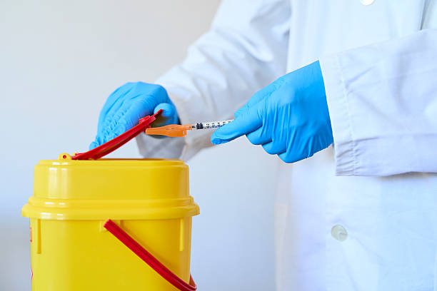 istock Doctor safely disposing hazardous  medical materials in bin over white background 2211031199