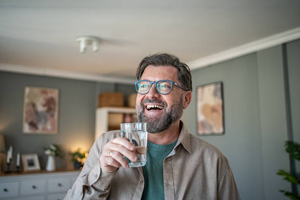 istock Happy mature man drinking water and smiling at home 2211033395