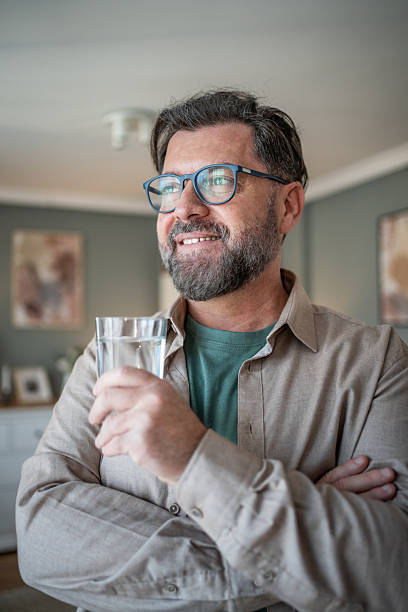 istock Smiling bearded man drinking water and looking away thoughtfully 2211033450