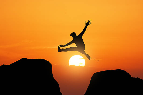 istock silhouette of a man jumping from one rock to another 2211036989