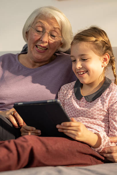 istock Joyful Grandmother And Young Girl Sharing Laughs While Using Tablet In Cozy Home Setting 2211038124