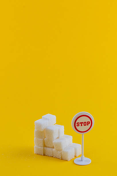 Sugar cubes stacked with stop sign against bright yellow backdrop
