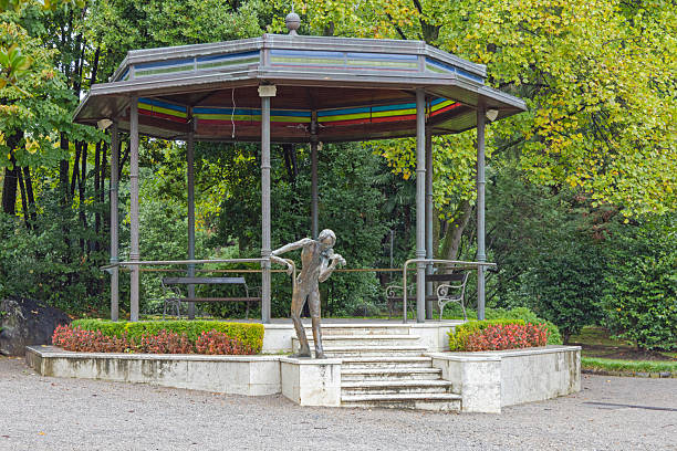 Winnipeg, Manitoba, August 10, 2012:  The Boy with a Boot statue in Assiniboine Park's English Garden in Winnipeg is a bronze sculpture depicting a young boy holding up a boot from which water flows.  It is a replica of a well-known 19th-century design, Originally created in Europe.  The statue is a charming focal point in the garden, surrounded by lush greenery and flowers, adding to the park's serene and picturesque atmosphere.
