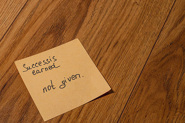 istock Inspirational note on wooden floor emphasizing the value of success 2211044540