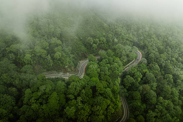 Aerial view curving highway in lush mountains, in mist on tropical island, Lombok
