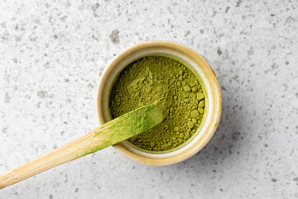 istock Matcha powder in a bowl with a bamboo spoon on marble background 2211049309