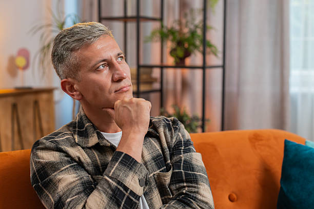 istock Thoughtful man rubbing chin looking aside with pensive expression pondering a solution at home room 2211058263