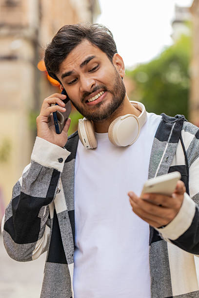 istock Stressed Indian man talking screaming on mobile phones having conflict quarrel complaint on street 2211060628