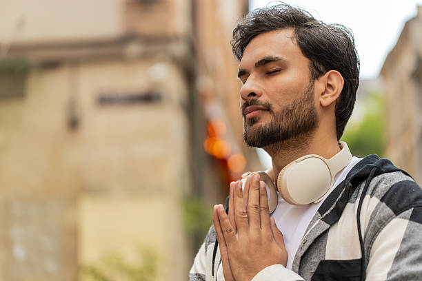 istock Religious Indian man praying with closed eyes to God asking for blessing while standing on street 2211060632