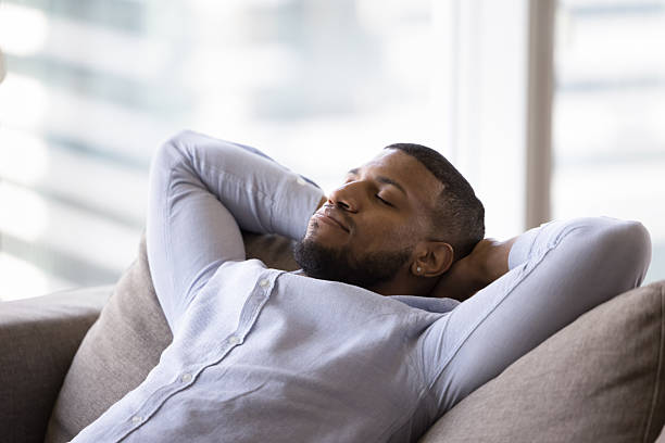 istock Calm African man rest leaned on soft sofa cushions 2211064583