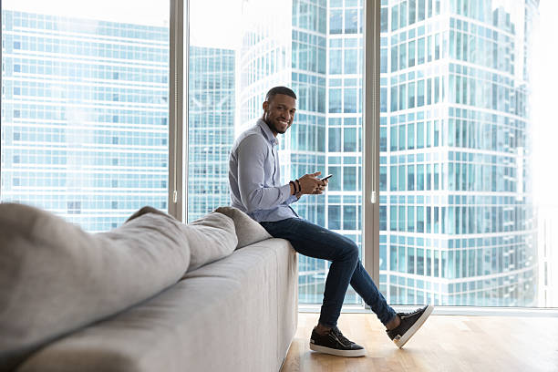 istock African man holds smartphone smile pose in modern skyscrapers apartment 2211064653