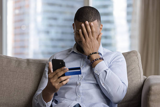 istock Man holds card and smartphone, feels upset due to scam 2211065152