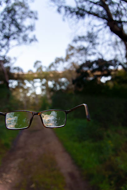 istock Eyeglasses reflecting sky above dirt road in forest 2211072735