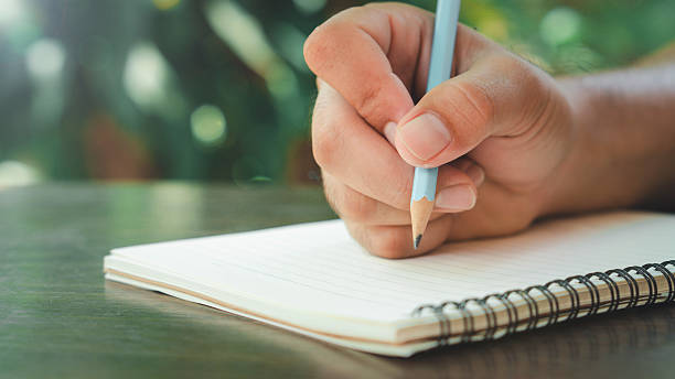 istock Man hand with pencil writing on notebook. focus on man hand holding pen 2211073028