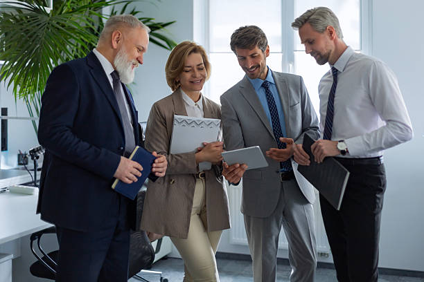 istock Four business people discussing work together using a tablet in a modern office 2211074683