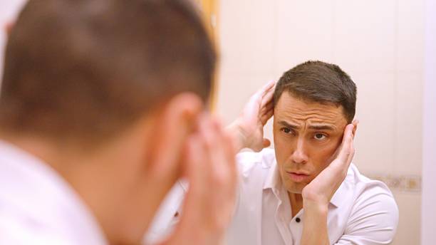 istock Smug man combing his hair very carefully 2211075737