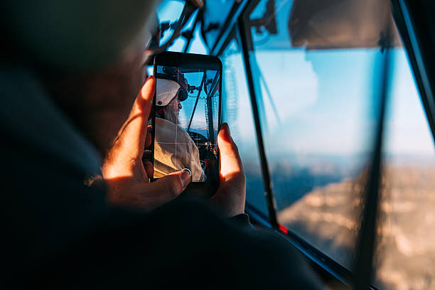 Young Man using a Smartphone to Photograph the Copper Canyon in Chihuahua Mexico while flying in a Single Propeller Aircraft