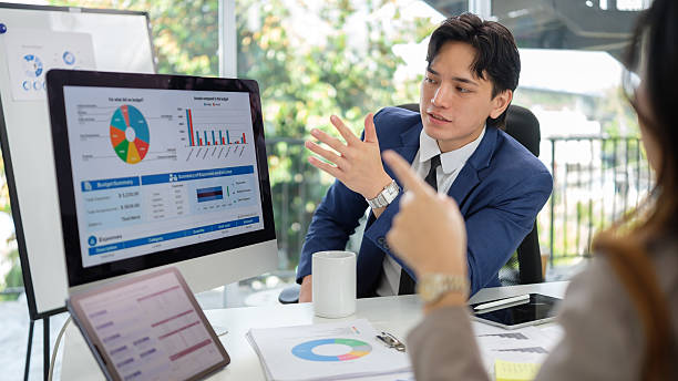 istock Professional businessman presenting and discussing financial data and charts with colleagues in a modern office. 2211077141