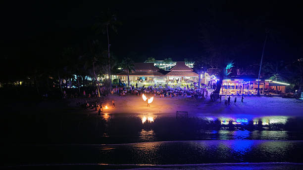 istock Fire dancer performing on beach at night with tourists watching 2211077656