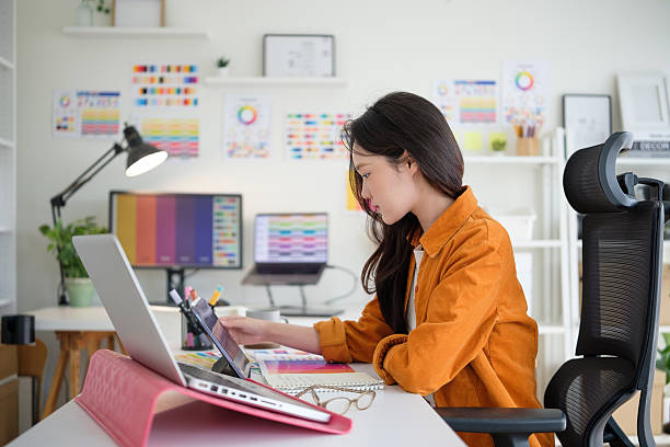 istock Young female designer concentrating on her project at a modern workspace with a laptop and color palettes. 2211077719