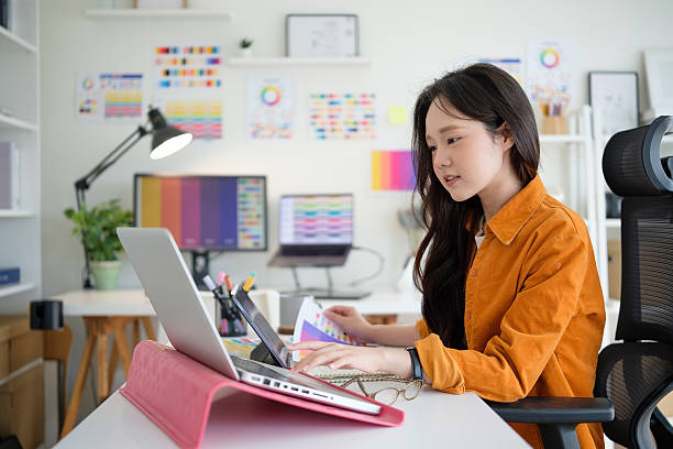 istock Young female designer concentrating on her project at a modern workspace with a laptop and color palettes. 2211077721
