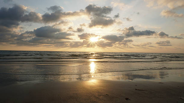 istock Sunset reflecting on wet sand with incoming waves and cloudy sky 2211077791