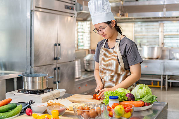 istock Chef Slicing fresh tomato on Wooden Cutting Board in Professional Kitchen 2211079339