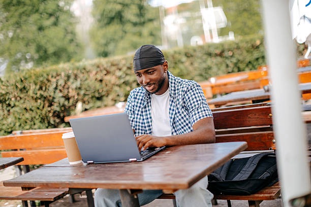 istock Young man spending time in outdoors cafe after work and using laptop 2211084089
