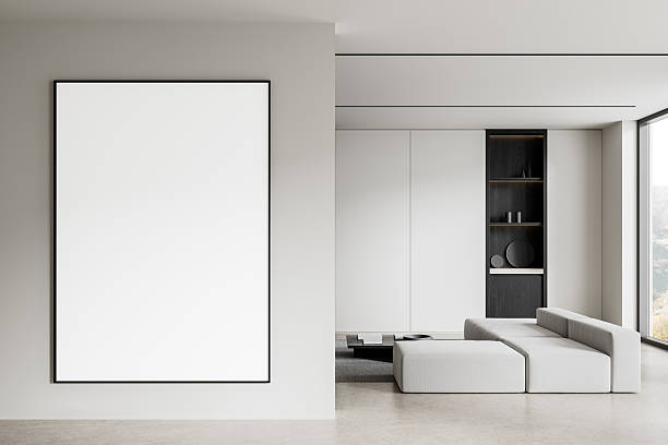 istock Modern minimalist living room interior with large vertical blank frame on wall and white modular sofa near dark accent shelf in soft daylight setting. 3D Rendering 2211084221