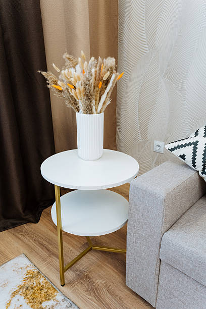 istock In a charming living room, there is a lovely white table that features a decorative vase filled with a beautiful arrangement of dried flowers, creating a warm and inviting atmosphere 2211090167