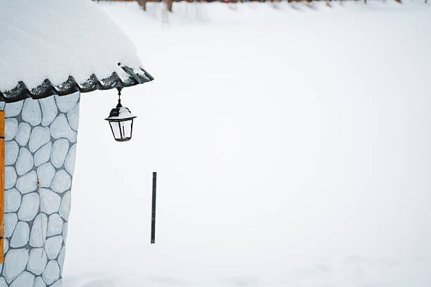 istock A stunning stone house covered in white snow features a charming vintage lamp hanging from the roof, creating an enchanting winter wonderland that captivates all who see it 2211090188